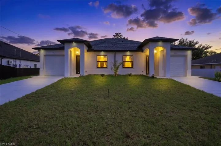View of front of house featuring a garage, stucco siding, and driveway