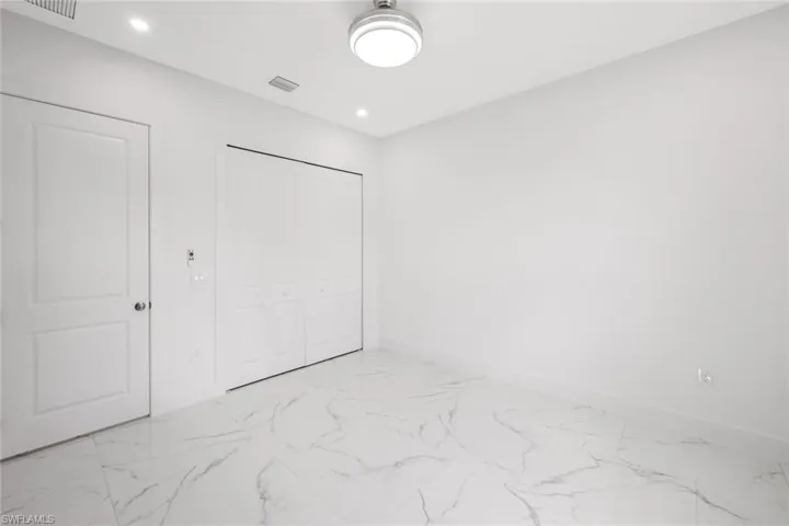Unfurnished bedroom with light marble finish flooring, recessed lighting, and a closet