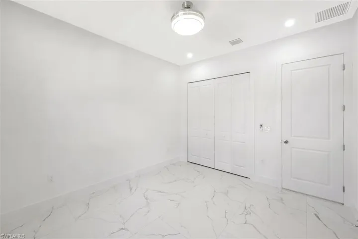 Unfurnished bedroom with light marble finish floors, a closet, and recessed lighting