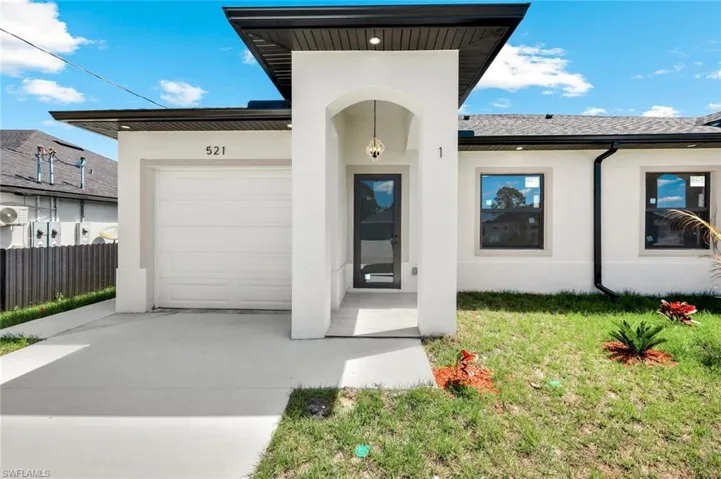 Property entrance featuring an attached garage, stucco siding, driveway, and a yard