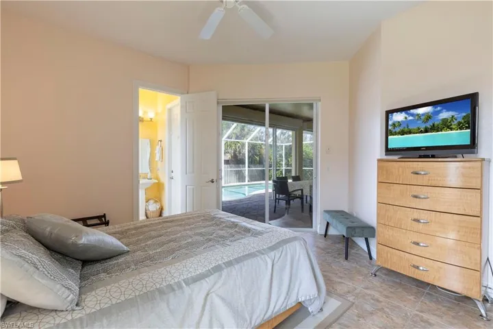 Bedroom with ceiling fan, ensuite bathroom, and access to exterior