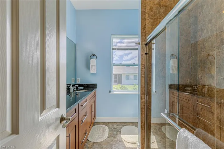 Bathroom with a healthy amount of sunlight, walk in shower, and vanity