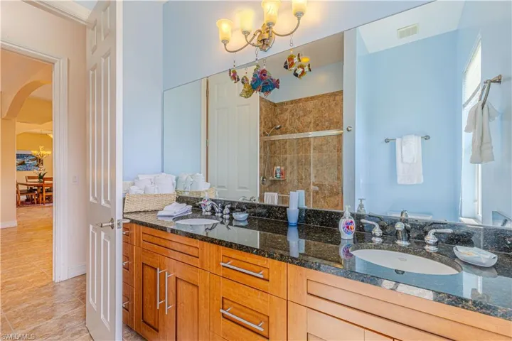Bathroom featuring tile patterned flooring, a tile shower, a chandelier, and vanity