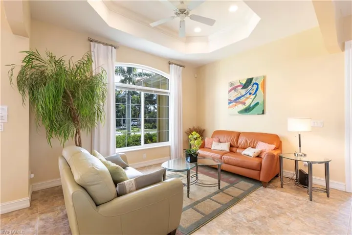 Living room with ceiling fan, a tray ceiling, ornamental molding, and a wealth of natural light