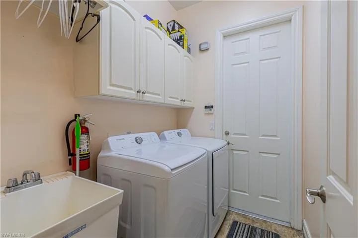 Clothes washing area featuring cabinets, separate washer and dryer, and sink