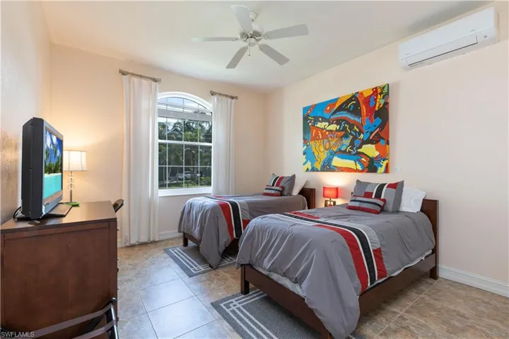 Bedroom featuring an AC wall unit, ceiling fan, and light tile patterned flooring