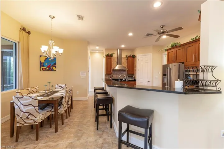 Kitchen with high end fridge, decorative backsplash, wall chimney exhaust hood, kitchen peninsula, and pendant lighting