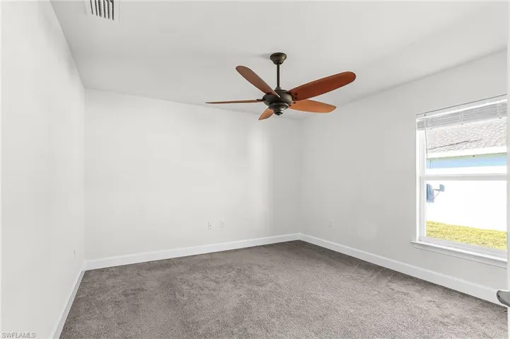 Carpeted spare room with baseboards and ceiling fan