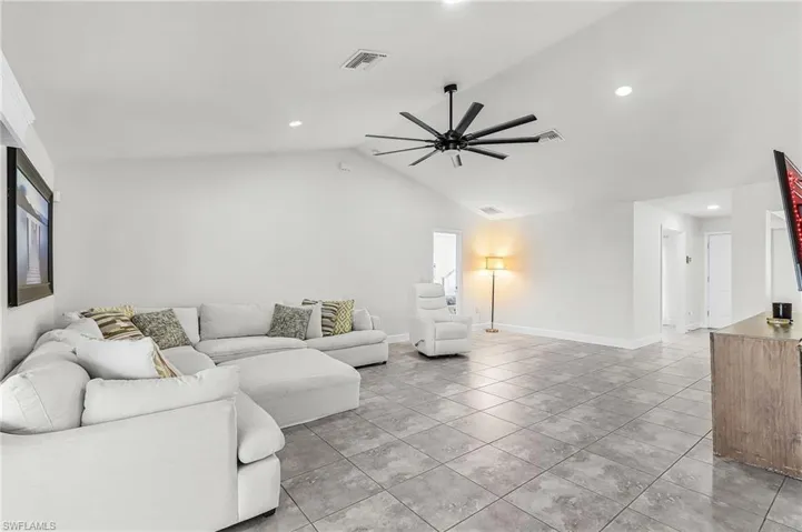 Living room featuring a ceiling fan, recessed lighting, light tile patterned floors, and a high ceiling