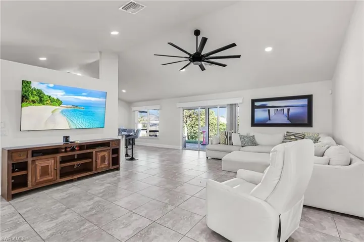 Living area featuring ceiling fan, light tile patterned flooring, lofted ceiling, and recessed lighting