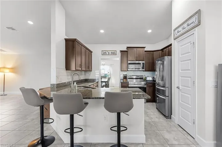 Kitchen featuring backsplash, a peninsula, stainless steel appliances, a kitchen breakfast bar, and recessed lighting