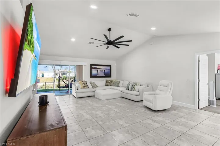 Living area featuring a ceiling fan, recessed lighting, lofted ceiling, and light tile patterned floors