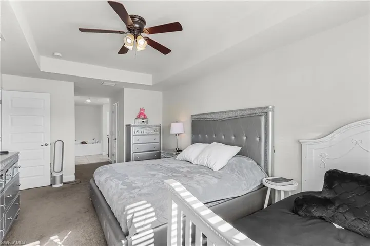 Bedroom featuring a tray ceiling, dark colored carpet, and a ceiling fan
