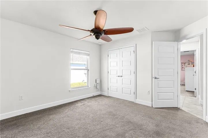 Unfurnished bedroom featuring carpet, a closet, and a ceiling fan