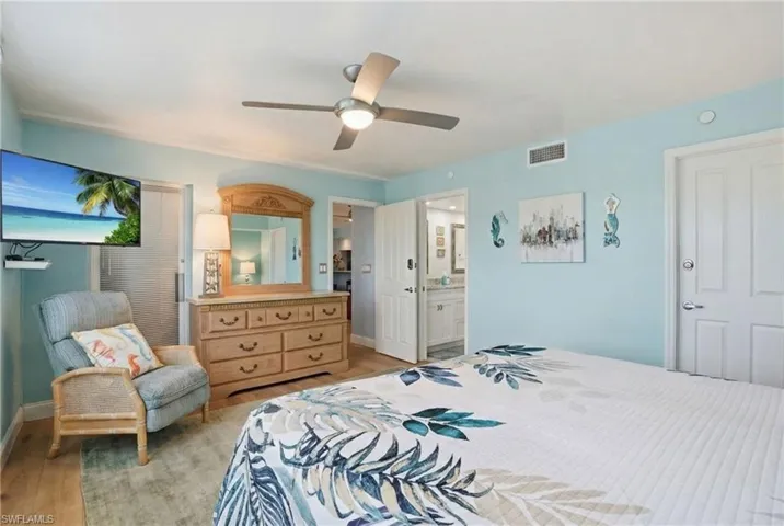 Bedroom featuring light wood-style flooring, a ceiling fan, and ensuite bathroom - Virtually Edited Image