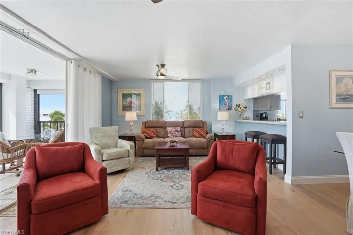 Living area featuring ceiling fan, light wood finished floors, and a textured ceiling - Virtually Edited Image