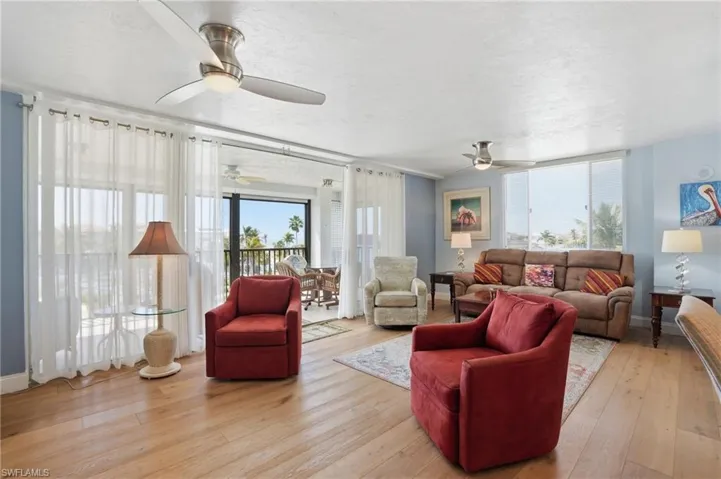 Living area featuring light wood-type flooring, a ceiling fan, and a textured ceiling - Virtually Edited Image