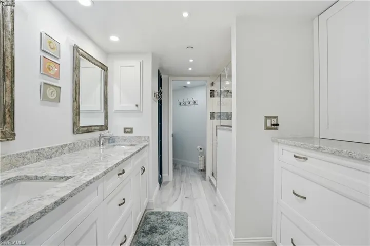 Full bath with double vanity, recessed lighting, a shower stall, and light wood finished floors - Virtually Edited Image