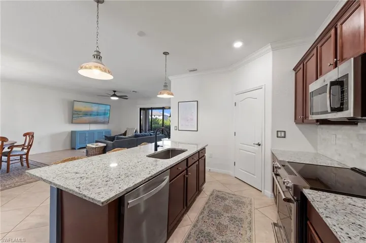 Kitchen island with an undermount sink, granite countertops, stainless steel appliances, and wood-finish cabinetry