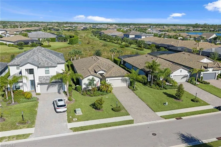 Residential neighborhood with paved streets and sidewalks, featuring landscaped properties with green lawns and mature palm trees