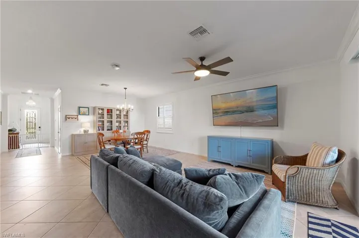 Open-concept living space featuring tile flooring, a ceiling fan, and crown molding