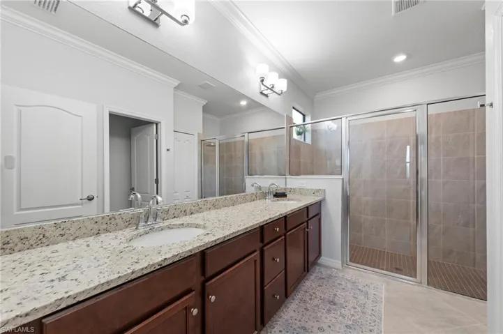 Dual vanity with stone countertop, wood-finish cabinetry, extra-large shower and undermount sinks