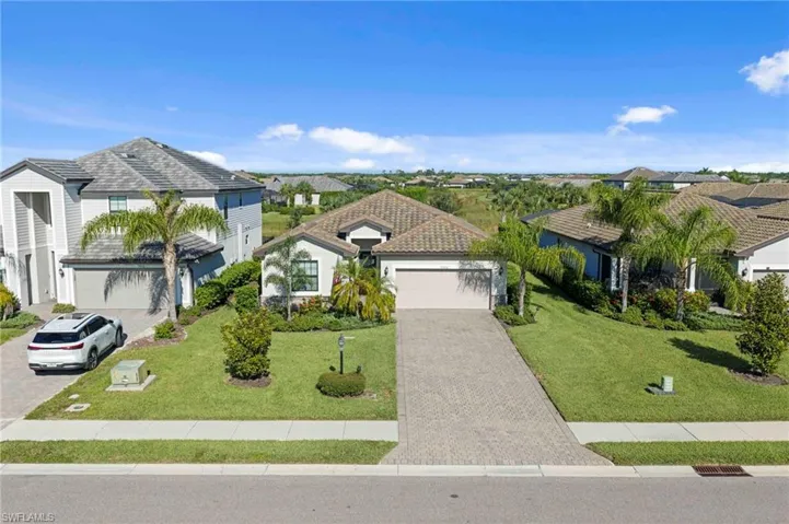 Single-story residence featuring a tile roof, an integrated garage, and a paver driveway