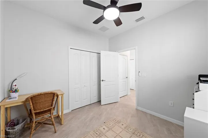 Neutral wall paint, ceiling fan with integrated lighting, tiled flooring, bi-fold closet doors, and a solid interior door