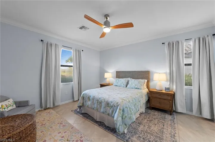 Crown molding, ceiling fan with wood-finish blades, and tiled flooring