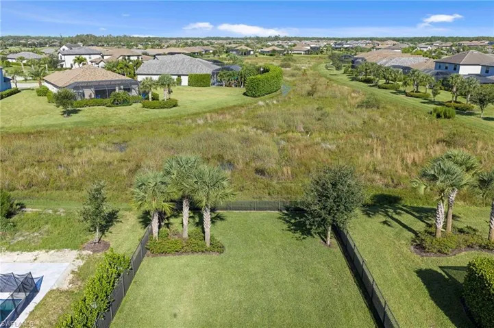 Fenced backyard with manicured lawn and mature landscaping. Preserve view.