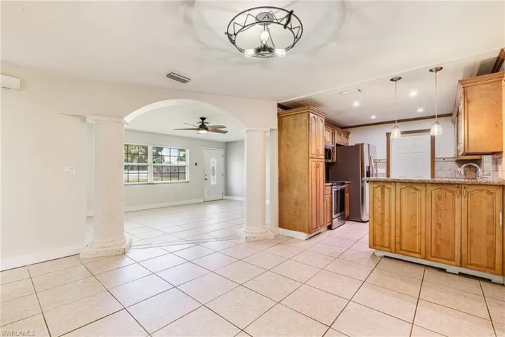 Kitchen with ceiling fan, ornate columns, pendant lighting, open floor plan, and light tile patterned floors