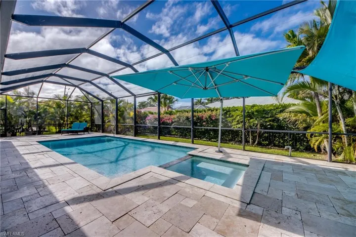 View of pool featuring glass enclosure, a sunroom, a pool with connected hot tub, and a patio
