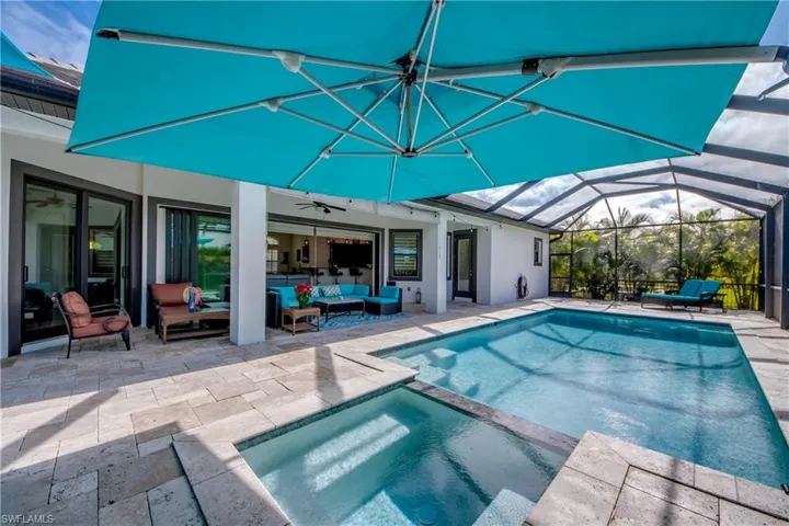 View of swimming pool featuring glass enclosure, a patio area, a pool with connected hot tub, and outdoor lounge area