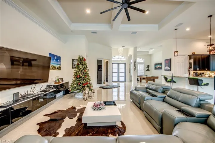 Living room with a ceiling fan, crown molding, light tile patterned floors, a towering ceiling, and french doors