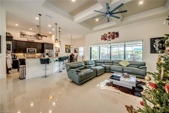 Living room with coffered ceiling, a ceiling fan, beam ceiling, a high ceiling, and crown molding