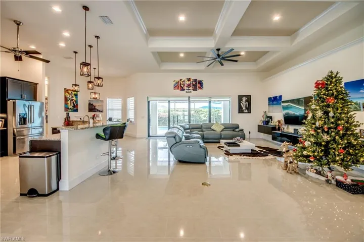Living area with a ceiling fan, coffered ceiling, beamed ceiling, a high ceiling, and ornamental molding