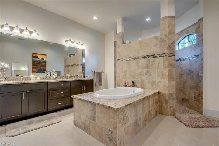 Full bath featuring a garden tub, double vanity, a walk in shower, and light tile patterned flooring