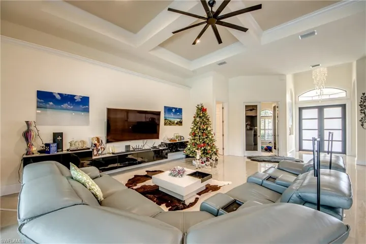 Living room with coffered ceiling, a high ceiling, ornamental molding, beamed ceiling, and a chandelier