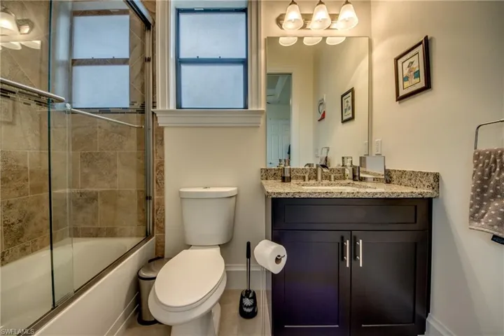 Bathroom featuring combined bath / shower with glass door and vanity