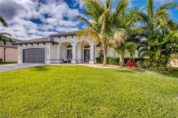 Mediterranean / spanish-style house with stucco siding, asphalt driveway, a garage, a front lawn, and a tile roof