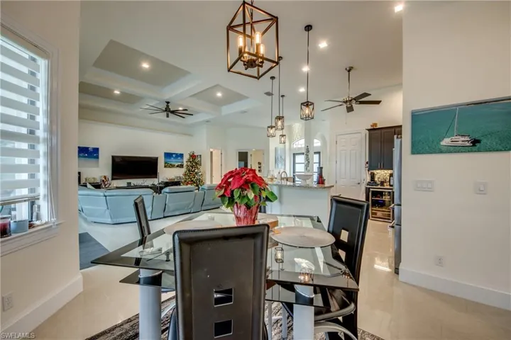 Dining room featuring coffered ceiling, a chandelier, a ceiling fan, beam ceiling, and beverage cooler