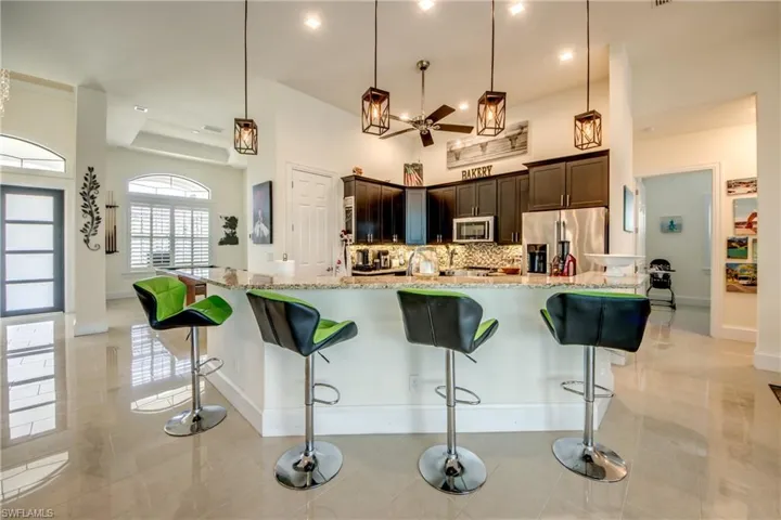 Kitchen featuring decorative light fixtures, light stone counters, a breakfast bar, appliances with stainless steel finishes, and recessed lighting