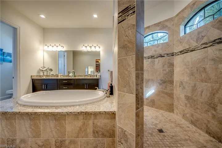 Bathroom featuring vanity, a garden tub, and a walk in shower