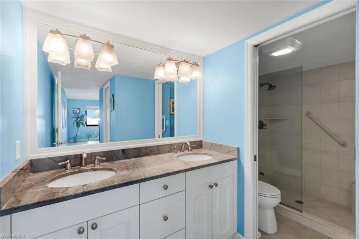 Full bathroom with double vanity, a tile shower, and light tile patterned floors