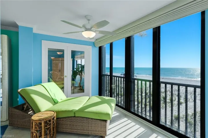 Sunroom with view of water and beach and ornamental molding