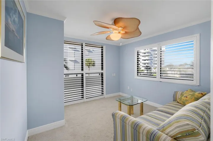 Living area with crown molding, light carpet, plenty of natural light, and ceiling fan