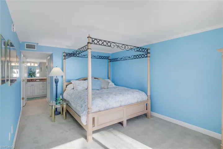 Bedroom featuring light colored carpet, ensuite bathroom, and crown molding