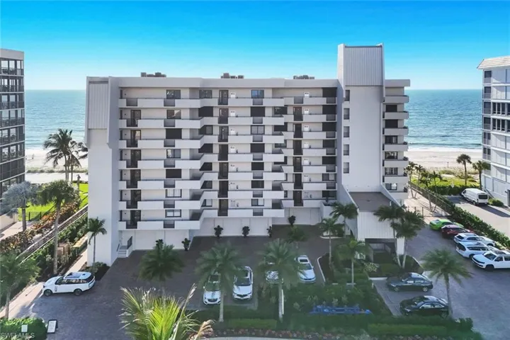 View of apartment building / complex featuring view of water and beach
