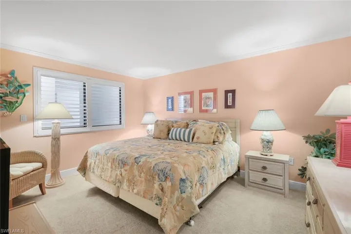 Bedroom with crown molding and light colored carpet