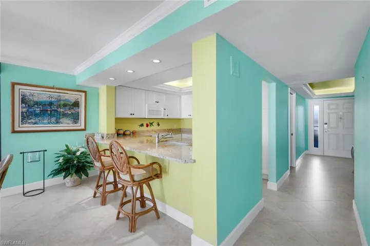 Hallway with ornamental molding, recessed lighting, a tray ceiling, and light tile patterned flooring